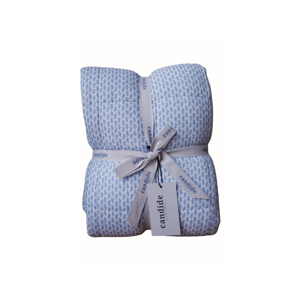 Couverture matelassée pour enfants en mousseline de coton Candide Living de motif Ondine en bleu chambray présentée avec ruban.