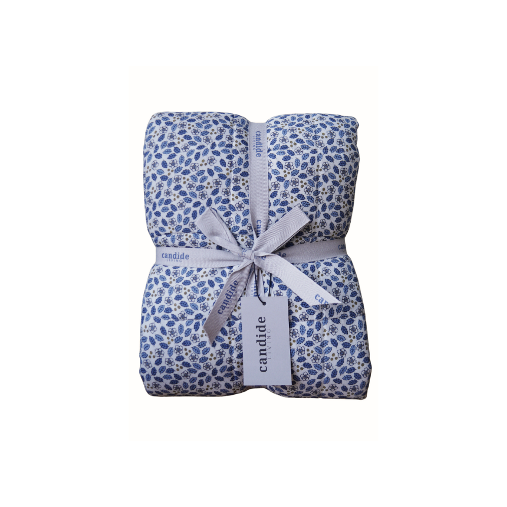 Couverture matelassée pour enfant en mousseline de coton Candide Living de motif Flora en bleu chambray présentée avec ruban. 