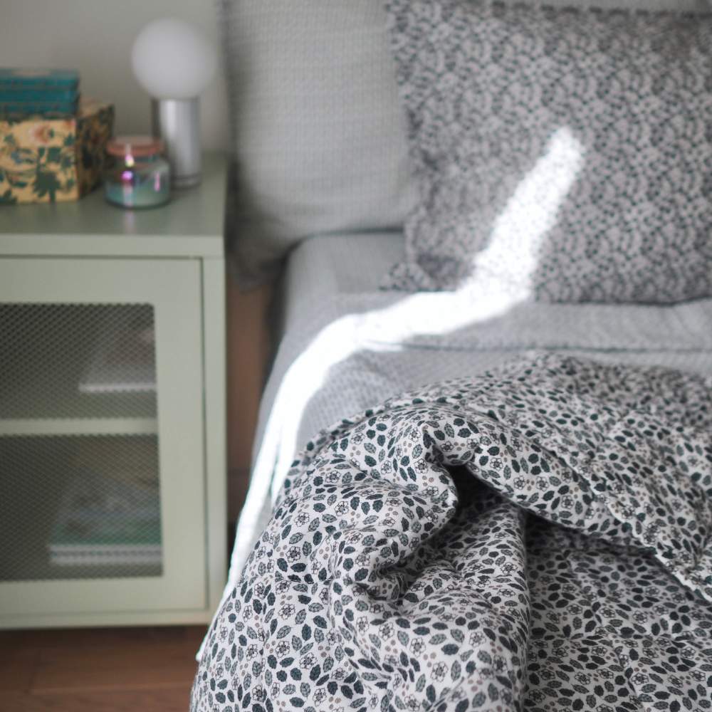 Couverture matelassée pour enfants en mousseline de coton Candide Living de motif Flora en vert sauge dans un décor de chambre d'enfant. 