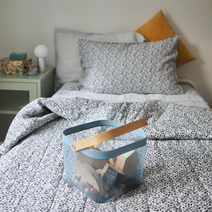 Couverture matelassée pour enfants en mousseline de coton Candide Living de motif Flora en vert sauge dans un décor de chambre d'enfant.