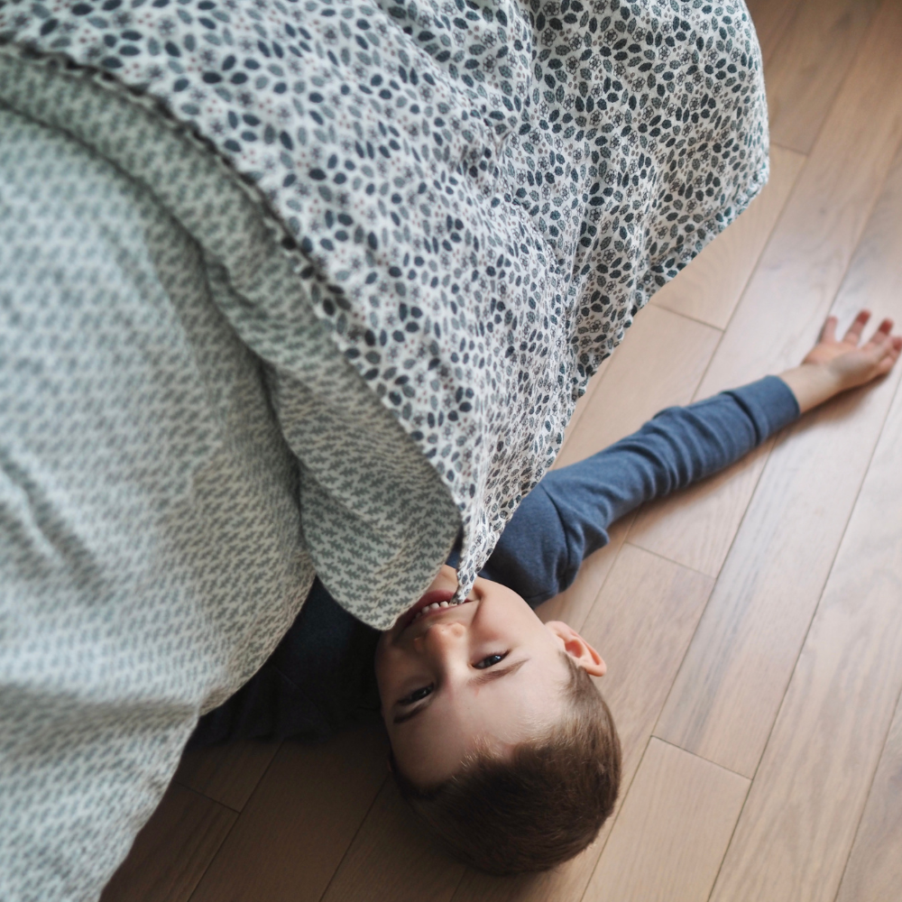 Ensemble de draps pour enfants en mousseline de coton Candide Living motif Flora vert sauge mis en scène avec un petit garçon. 