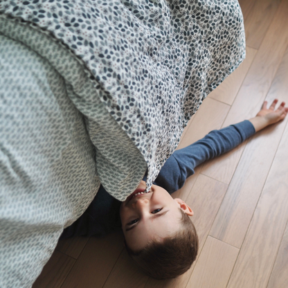 Ensemble de draps pour enfants en mousseline de coton Candide Living motif Flora vert sauge mis en scène avec un petit garçon. 