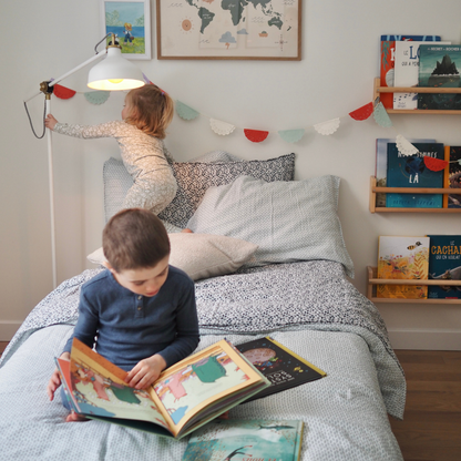 Ensemble de draps pour enfants en mousseline de coton Candide Living motif flora vert sauge dans une chambre d'enfant avec deux enfants. 