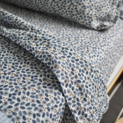 Gros plan sur l’ensemble de draps pour enfant en mousseline de coton Candide Living, motif Flora en bleu chambray.