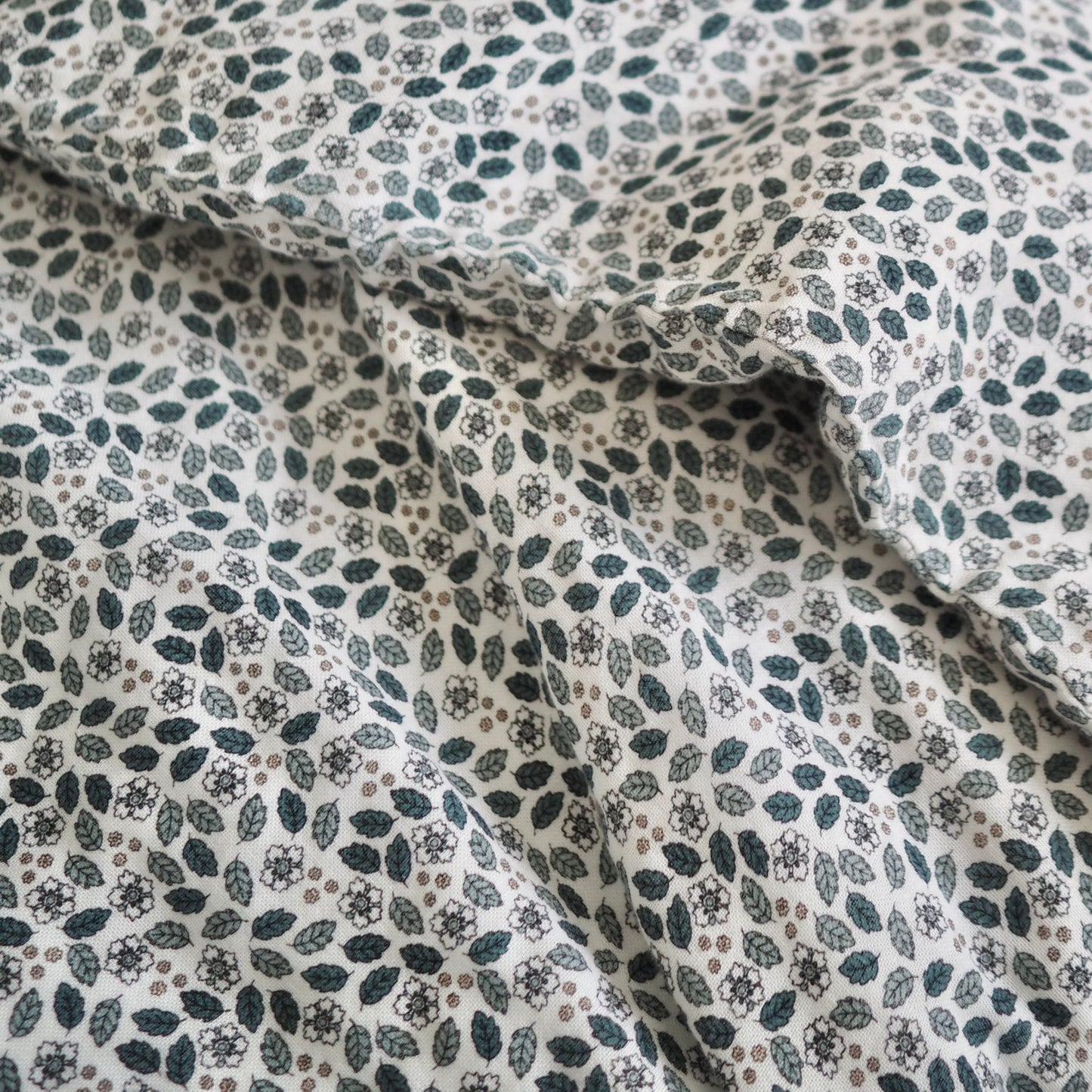 Gros plan sur l'ensemble de draps pour enfants en mousseline de coton Candide Living de motif Flora vert sauge.