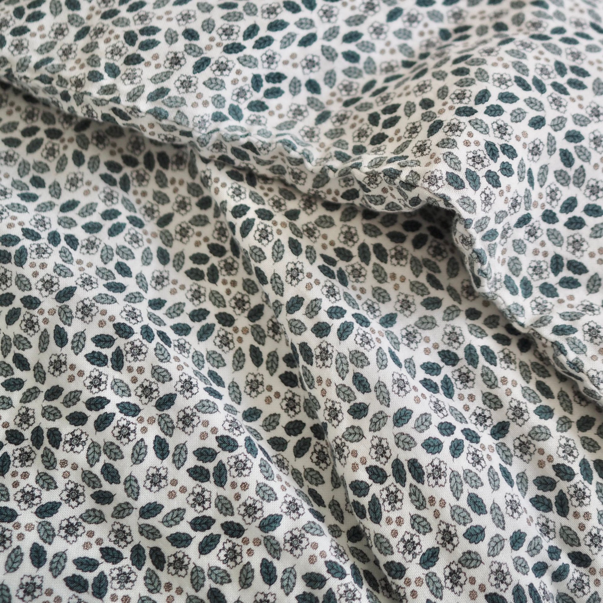 Gros plan sur l'ensemble de draps pour enfants en mousseline de coton Candide Living de motif Flora vert sauge.