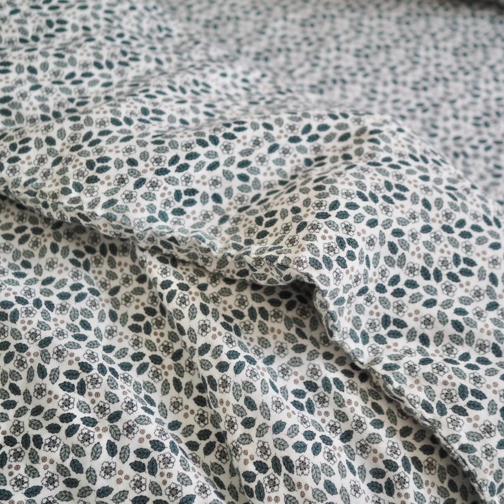 Gros plan sur l'ensemble housse de couette pour enfant en mousseline de coton Candide Living, motif Flora en vert sauge.