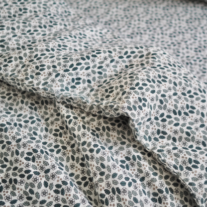 Gros plan sur l'ensemble housse de couette pour enfant en mousseline de coton Candide Living, motif Flora en vert sauge.
